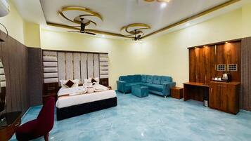 A spacious bedroom with a large bed, a blue sofa, a wooden wardrobe, and a red chair.
