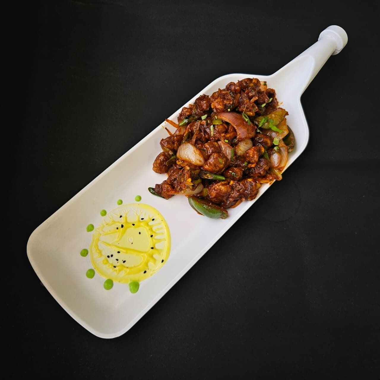Un plato de carne salteada con verduras, sobre un plato blanco y adornado con limón.