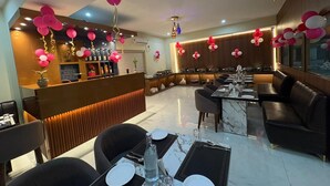 Ein modernes Restaurant mit Barbereich, Marmortischen und schwarzen Ledersitzmöbeln.