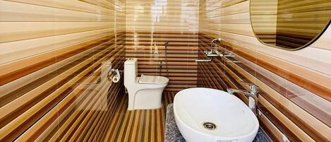 Une petite salle de bain aux murs rayés, avec un lavabo blanc et une douche.