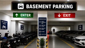 Un área de estacionamiento subterráneo con espacios definidos para motocicletas y automóviles, flechas direccionales para la entrada y salida, y un cartel que indica las normas de estacionamiento.