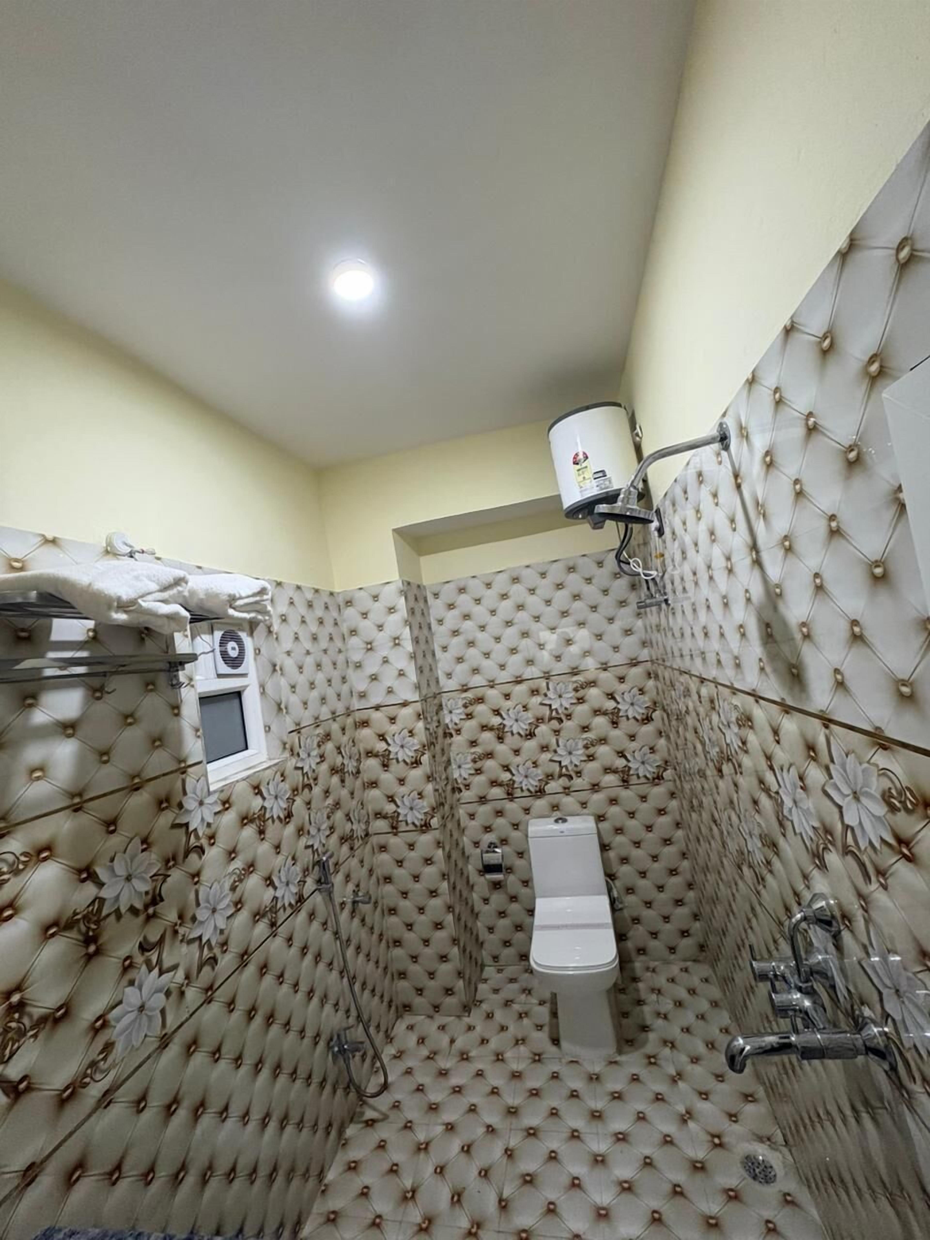 A bathroom with a toilet, shower, and a towel rack.