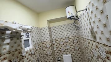 Un baño con inodoro, ducha y barra para toallas.