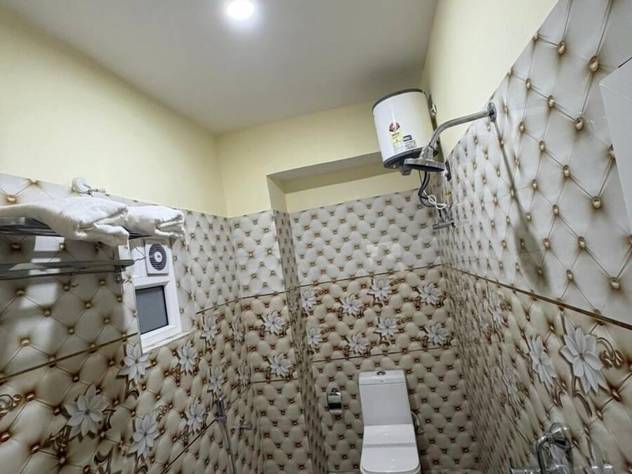 Un baño con inodoro, ducha y barra para toallas.