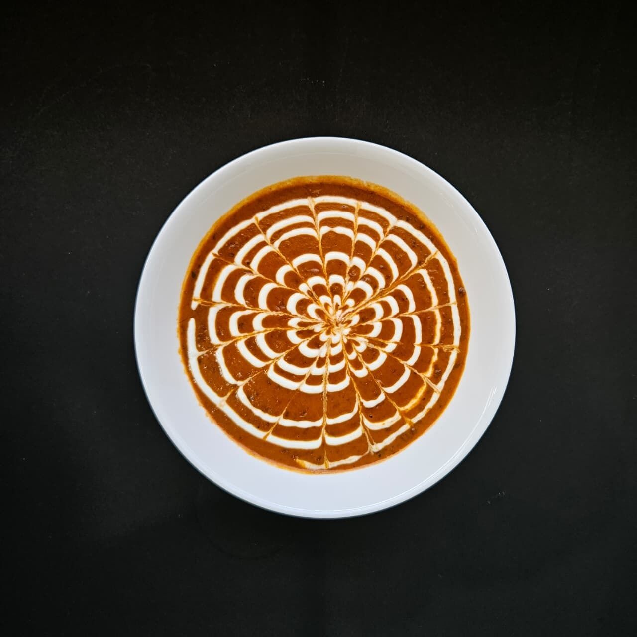 Una taza de café con leche con un diseño decorativo sobre una superficie oscura.