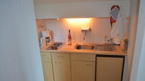 Kompakti keittiö, jossa on puiset kaapit, ruostumattomasta teräksestä valmistettu pesuallas ja kahvinkeitin.