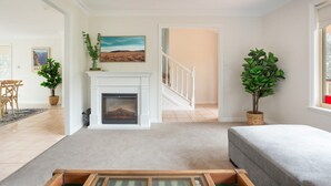 A living room with a fireplace, a staircase, and a view of the outdoors. - Stunning Katoomba Home with Lush Garden&Playground (Katoomba)