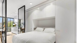 Een moderne slaapkamer met een groot bed, een bureau en een stoel.