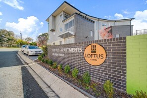 Ein modernes Mehrfamilienhaus mit einem Schild, das "LOFTUS APARTMENTS 89 Allan Street" anzeigt.