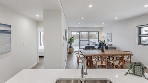 Una cocina moderna con una mesa y sillas de madera, una encimera blanca y un fregadero.