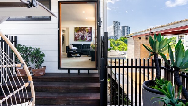 Une maison moderne avec un balcon, un canapé noir et un tableau.