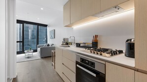 Eine moderne Küche mit Einbauherd, Backofen und Spüle. Es gibt einen Essbereich mit einem grauen Sofa und einem kleinen Tisch.