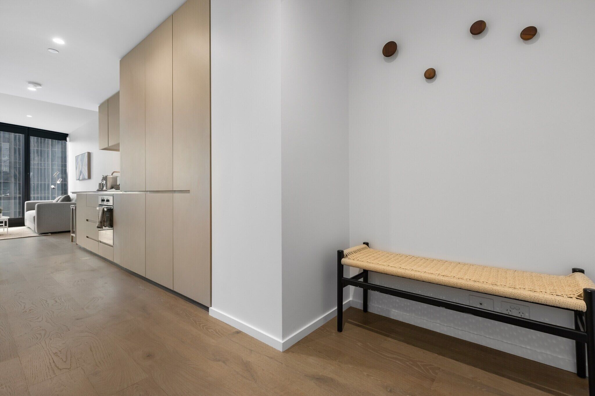 Una cucina moderna con elettrodomestici integrati, una panca con seduta in vimini e un'ampia finestra vista città.
