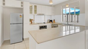 Een moderne keuken met witte kastjes, een roestvrijstalen koelkast, een inbouwoven en een groot kookeiland met spoelbak.