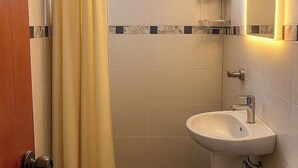 Une salle de bain avec un lavabo, un miroir et un espace douche.