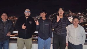 Un groupe de personnes se tient sur un balcon, avec une vue sur la ville en arrière-plan.