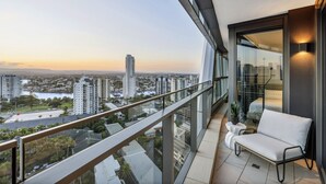 A balcony with a view of a cityscape, a white sofa, and a small table with a plant. - Jewel Luxury Beachside 2-Bed with Water View (Surfers Paradise)