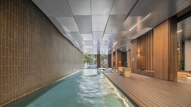 A modern indoor swimming pool with a wooden deck and tiled walls. - 1BR Apartment Near CBD with Pool (Docklands)