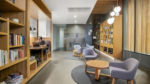 A modern library with bookshelves, a laptop user, and seating areas. - 1BR Apartment Near CBD with Pool (Docklands)