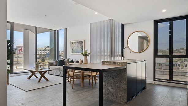 A modern living space with a kitchen island, dining area, and large windows offering city views. - Spacious 2-Bed Apartment with Rooftop Views (North Fremantle)