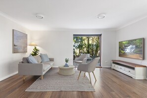 Una sala de estar moderna con un sofá, dos sillones, una mesa de centro y un mueble para televisor.
