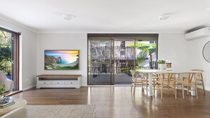 Un ampio soggiorno con un grande quadro, un'area pranzo con sedie in legno e una porta scorrevole in vetro che dà su un balcone.