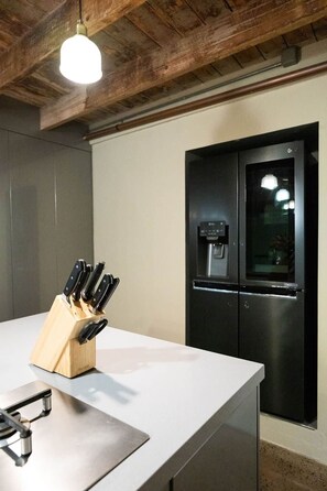 A kitchen with a stainless steel refrigerator, a knife block, and a hanging light fixture. - Rosewood Terrace (Bathurst)