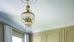 Une pièce comprenant un grand lit, un canapé, un lustre et une fenêtre avec des rideaux.