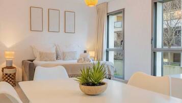Habitación de hotel con cama, una mesa de comedor, una planta en maceta y ventana con vistas a árboles.