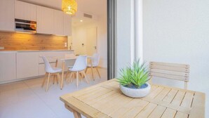 Una cocina moderna con armarios blancos, encimera de madera y una lámpara colgante.
