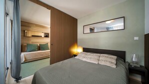 A bedroom with a bed, bedside table, lamp, and a mirror on the wall. - C. du Verdon N°3307 - 2P6 (Allos)