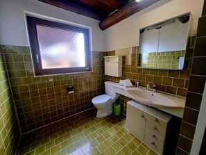 A bathroom with a toilet, sink, and window. - Casa RuKi (Capriasca)