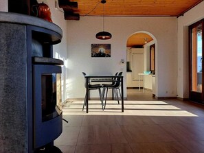 A modern kitchen with a built-in stove, a dining area with a table and chairs, and an arched doorway leading to another room. - Casa RuKi (Capriasca)