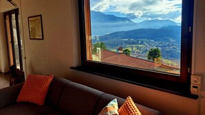 A room with a large window overlooking a mountainous landscape. - Casa RuKi (Capriasca)