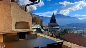 An outdoor dining area with a stone barbecue grill, a table, and chairs. - Casa RuKi (Capriasca)