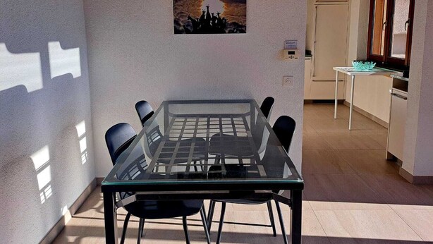 A dining area with a glass table and chairs, a pendant light, and a painting on the wall. - Casa RuKi (Capriasca)