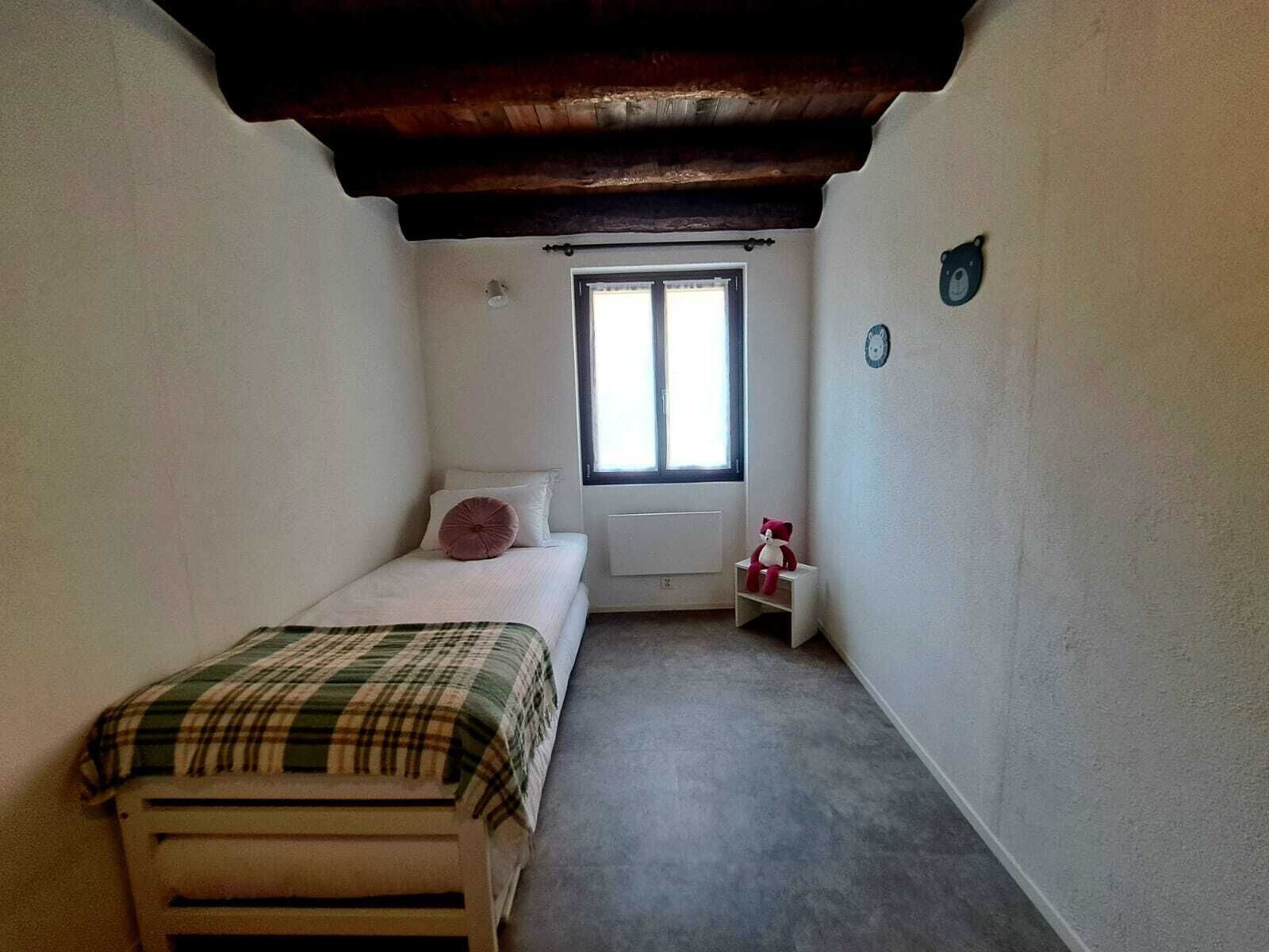 A small, narrow room with a single bed, a window, and a radiator.