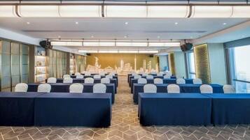 A conference room with rows of tables and chairs, a patterned carpet, and a cityscape mural on the back wall.