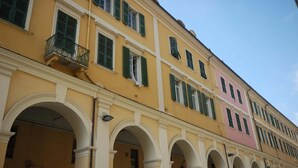 A row of yellow buildings with green shutters and white arches. - Ferienwohnung für 4 Personen in Imperia (Imperia)