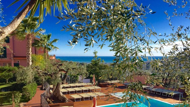 Uma área de piscina com espreguiçadeiras e vista para o mar.