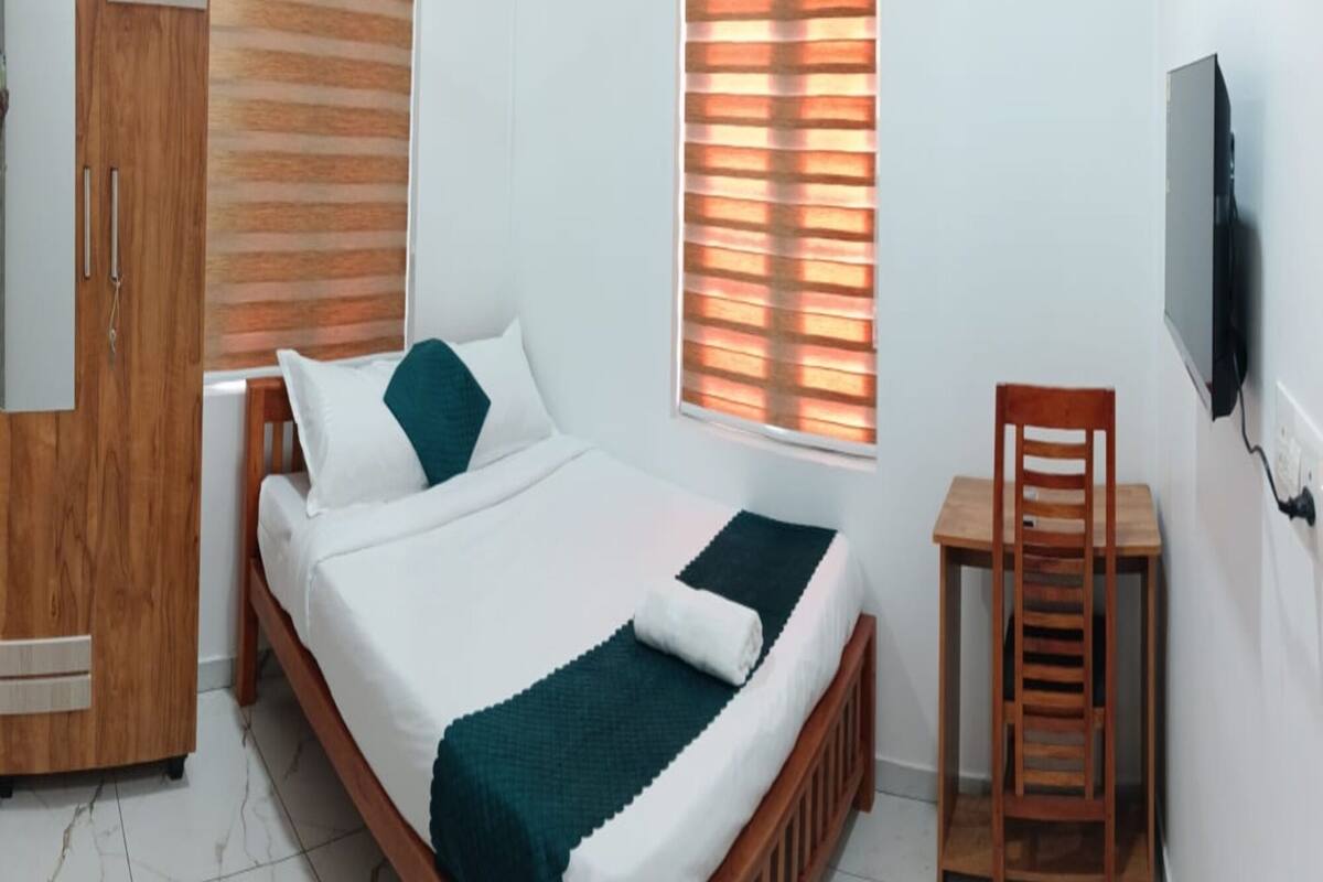 Ein Schlafzimmer mit Bett, Schreibtisch, Stuhl, Kleiderschrank und Fernseher.