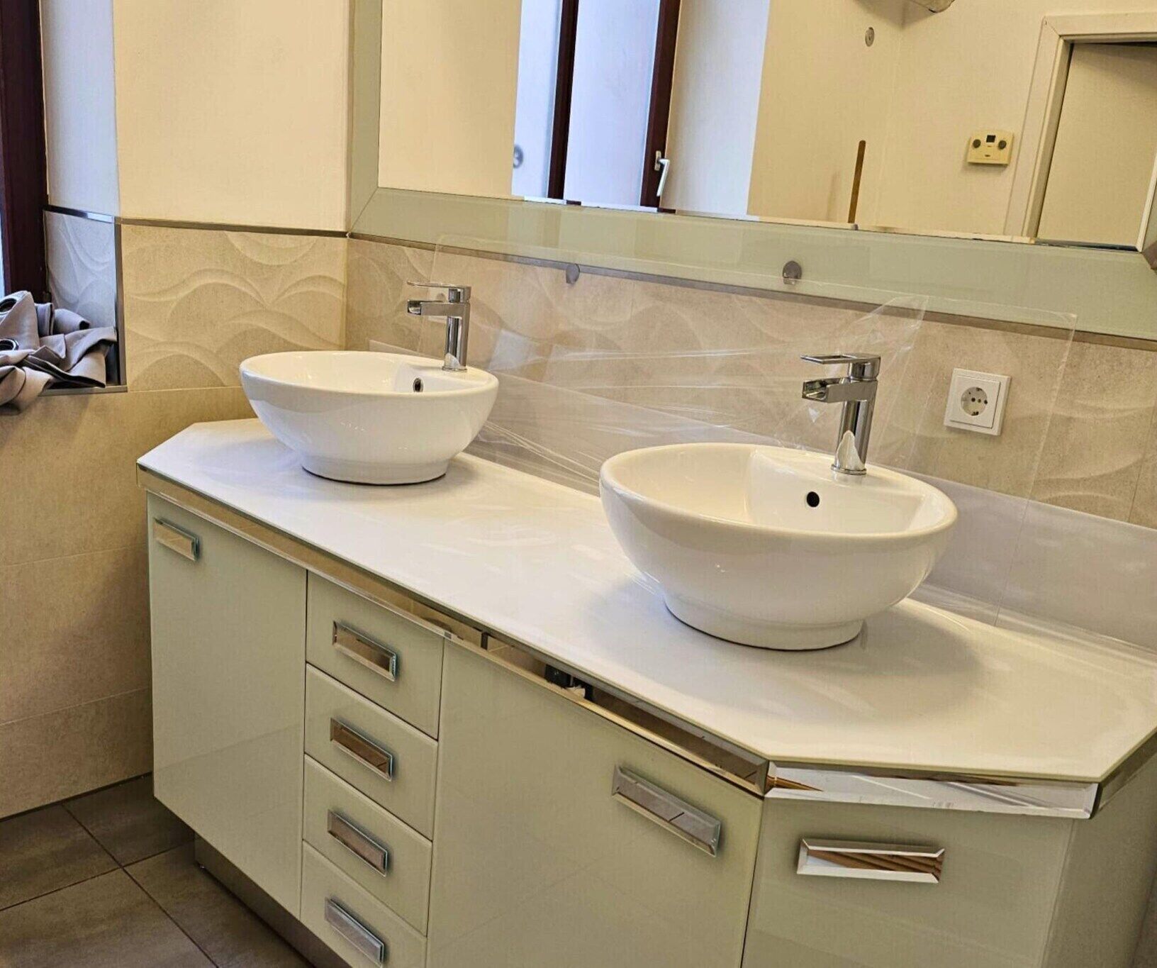 A bathroom with two vessel sinks, a large mirror, and a cabinet with drawers.