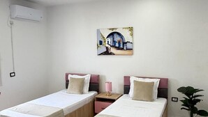 Een moderne slaapkamer met twee bedden, een plafondventilator, een airconditioning en een schilderij aan de muur.