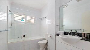 Un bagno moderno con doccia vetrata, vaso sospeso e mobile lavabo con lavandino e specchio.