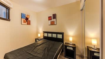 A hotel room with a bed, bedside tables, and wall art.