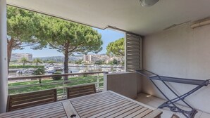 Ein Balkon mit Holztisch und -stühlen, einer Wäscheleine und Blick auf einen Hafen mit Booten und Gebäuden.