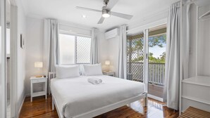 Quarto com cama, ventilador de teto, janela e varanda.