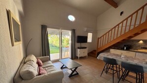 Uma sala de estar com sofá, mesa de centro e cozinha com mesa e cadeiras.
