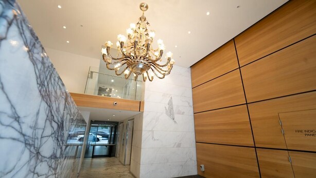 Un interior moderno con una pared de mármol, una pared revestida de madera y un candelabro.