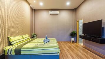 A modern hotel room with a bed, a flat-screen TV, an air conditioning unit, and a wooden floor.